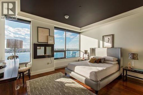 A bedroom with a large bed and a view of the water outside the window.