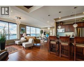 A living room with a large window and a dining area with chairs.