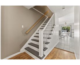 A staircase with a wooden handrail and white balusters leads to a dining area.