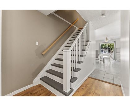 A staircase with a wooden handrail and white balusters leads to a dining area.