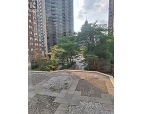 A rooftop garden with a gravel area and a grassy area with trees.