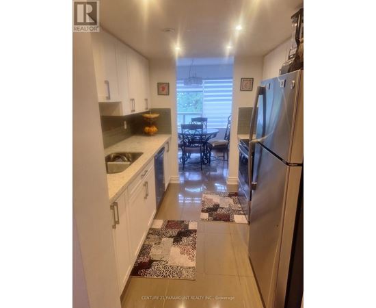 A kitchen with white cabinets and a refrigerator.