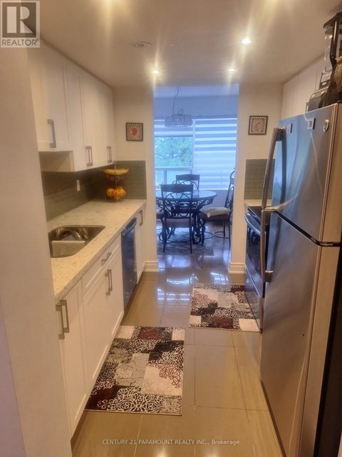 A kitchen with white cabinets and a refrigerator.