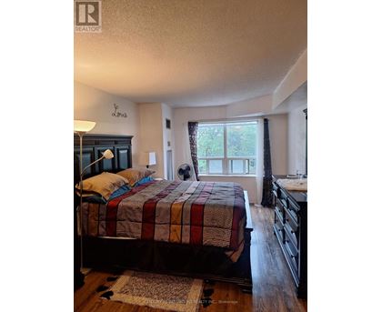 A bedroom with a bed, dresser, and window.