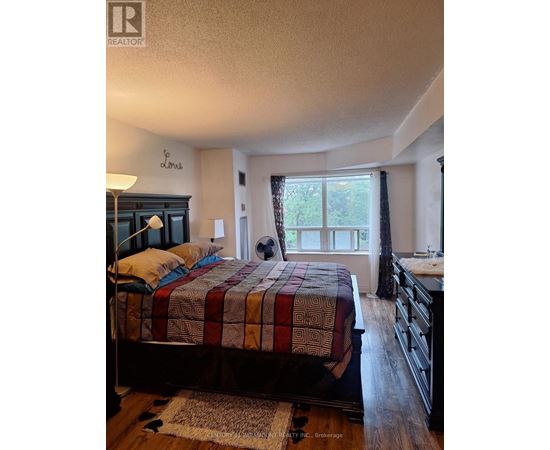 A bedroom with a bed, dresser, and window.