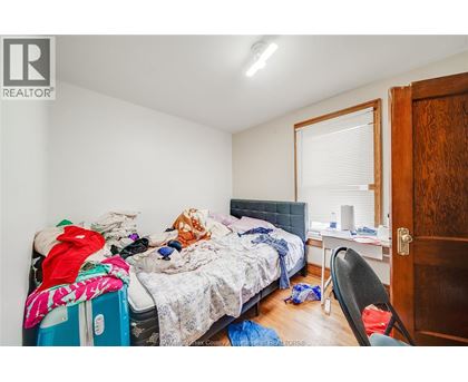 A messy bedroom with a bed, chair, and window.
