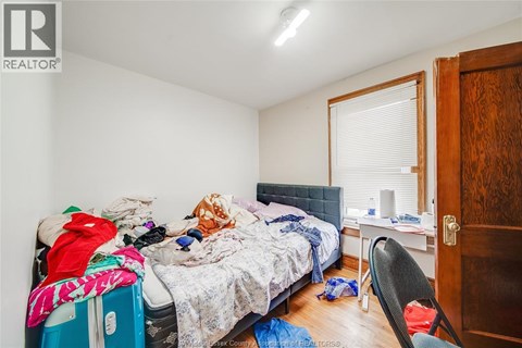 A messy bedroom with a bed, chair, and window.