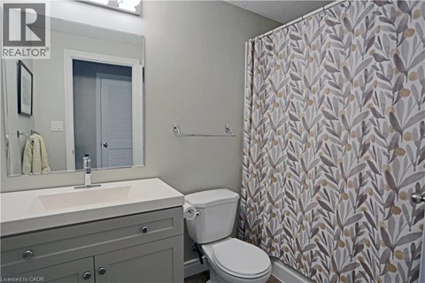 A bathroom with a toilet, sink, and shower curtain.