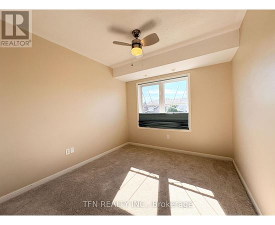 A room with a ceiling fan and a window letting in sunlight.