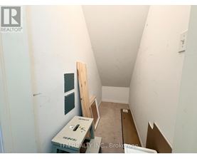 A room with a white wall and a wooden plank on the floor.