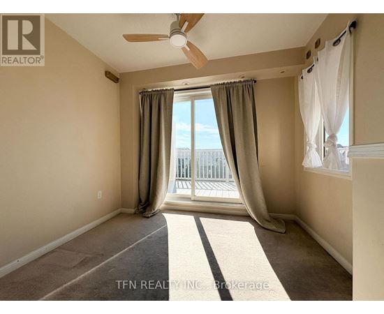 A room with a ceiling fan and a view of a balcony.