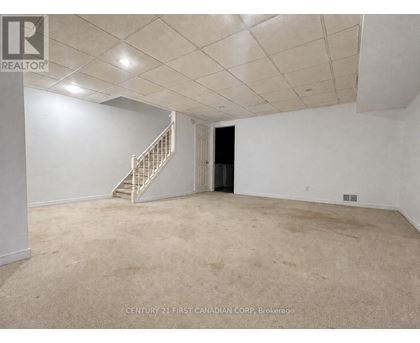 A spacious room with a staircase and a door.