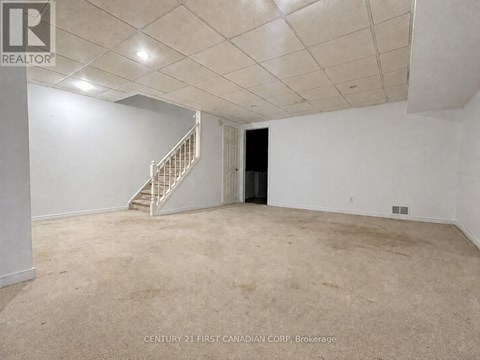 A spacious room with a staircase and a door.