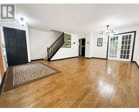 A room with wooden flooring and a staircase.