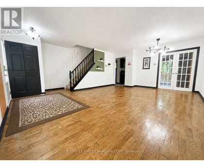A room with wooden flooring and a staircase.