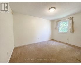 A room with a window and a carpeted floor.