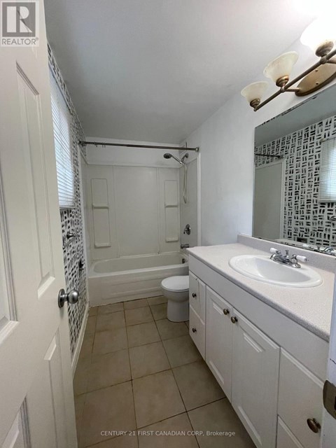 A white bathroom with a toilet, sink and shower.