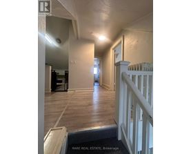A hallway with a white railing and wooden floors.