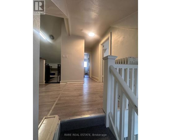 A hallway with a white railing and wooden floors.