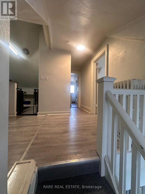 A hallway with a white railing and wooden floors.