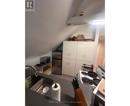 A kitchen with a sink, stove, and cabinets.