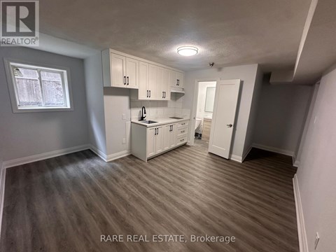 A kitchen area with white cabinets and a window.