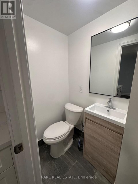 A white toilet sits in a small bathroom next to a sink.
