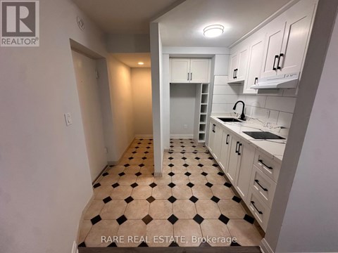 A kitchen with white cabinets and a checkered floor.