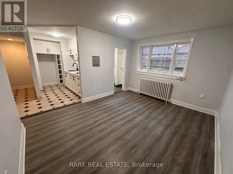 A room with wood flooring and a window with white blinds.