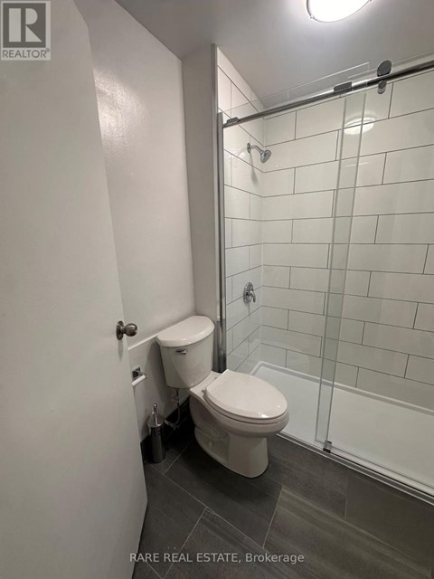 A white toilet in a small bathroom with a glass shower door.