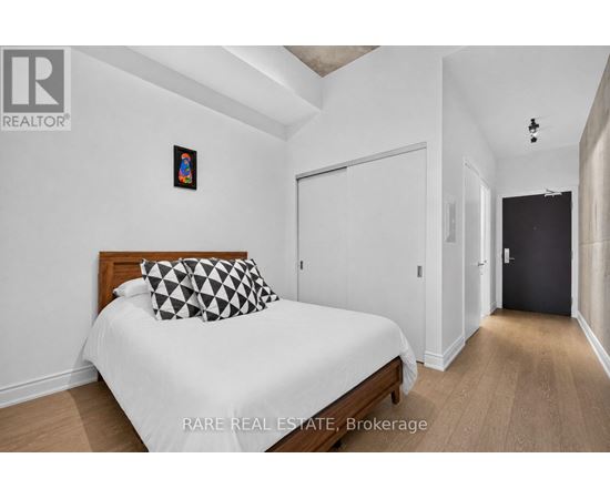 A bedroom with a bed, a pillow, and a picture on the wall.