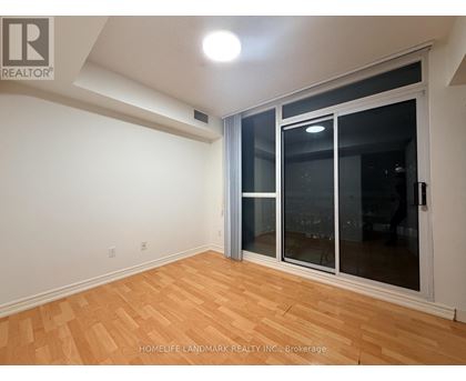 A room with a sliding glass door and wooden flooring.