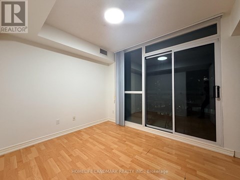 A room with a sliding glass door and wooden flooring.