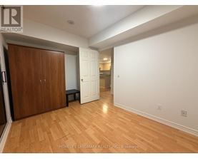 A room with wooden floors and white walls, with a wooden door on the left and a white door on the right.