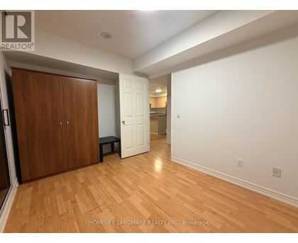 A room with wooden floors and white walls, with a wooden door on the left and a white door on the right.