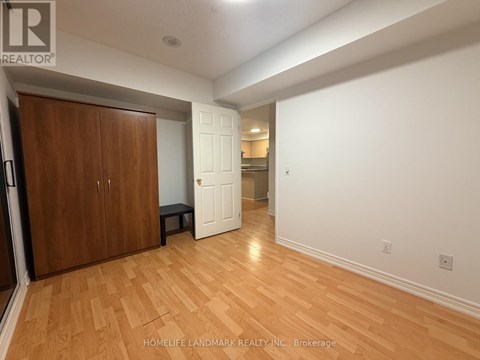 A room with wooden floors and white walls, with a wooden door on the left and a white door on the right.