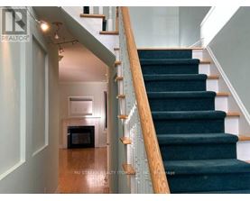 A staircase with a wooden handrail and green carpeted steps.