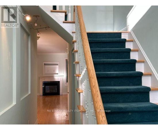 A staircase with a wooden handrail and green carpeted steps.