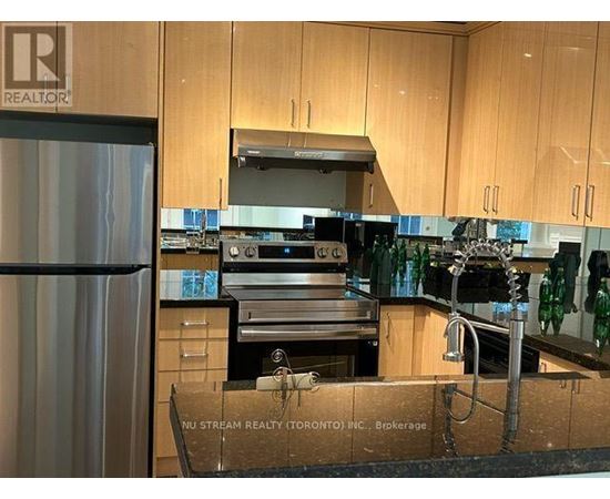 A kitchen with wooden cabinets and a stainless steel refrigerator.