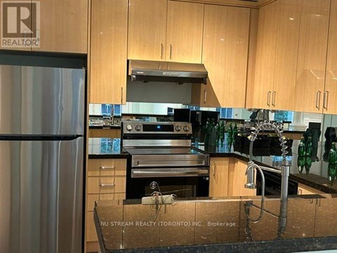 A kitchen with wooden cabinets and a stainless steel refrigerator.