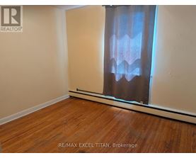 A room with wooden flooring and a window with curtains.