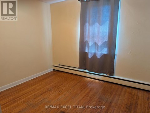 A room with wooden flooring and a window with curtains.