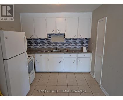 A kitchen with white cabinets and a white refrigerator.