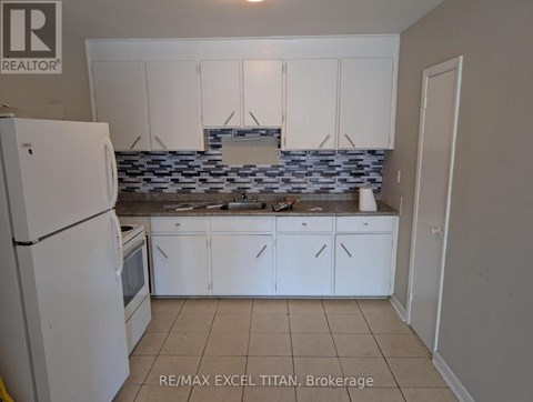A kitchen with white cabinets and a white refrigerator.