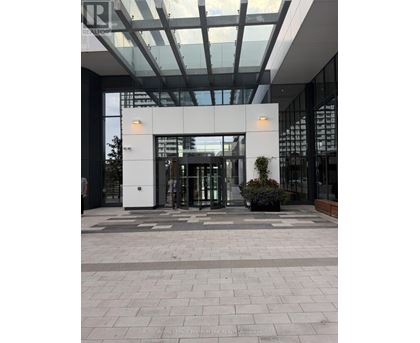 The entrance to a building with glass doors and a plant in front.