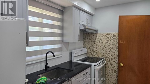 A kitchen with a stove, sink, and cabinets.