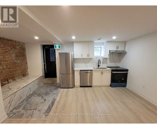 A kitchen with a brick wall and stainless steel appliances.