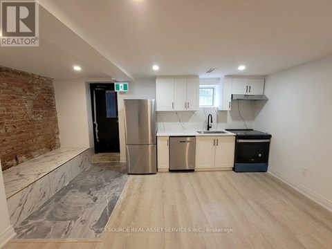 A kitchen with a brick wall and stainless steel appliances.