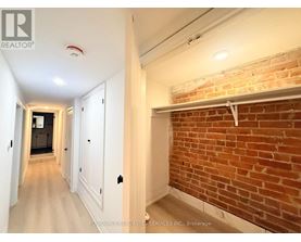 A hallway with a brick wall on one side and white walls on the other.