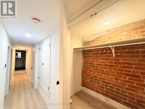 A hallway with a brick wall on one side and white walls on the other.